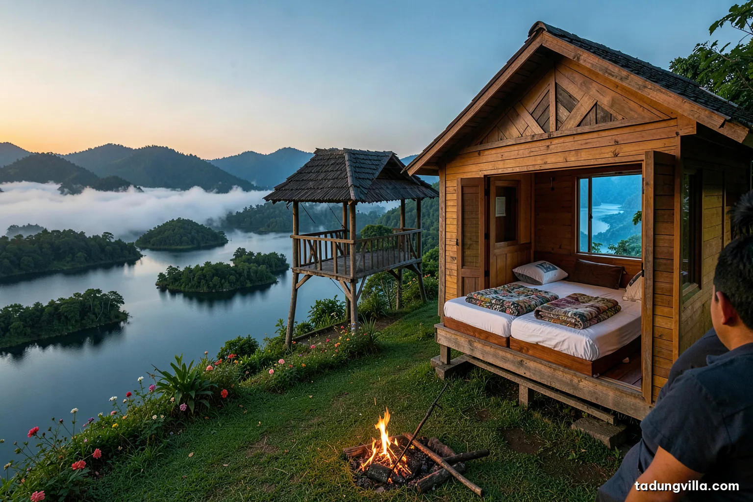 Bright bedroom inside a wooden villa with two neatly made beds, extra folded blankets and pillows, a window open to a blue lake and green hills