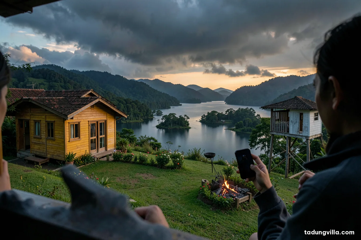 Over-the-shoulder view of a person holding a phone with a blank dark display on a villa veranda, heavy grey storm clouds gathering over a wide reservoir and forested hills